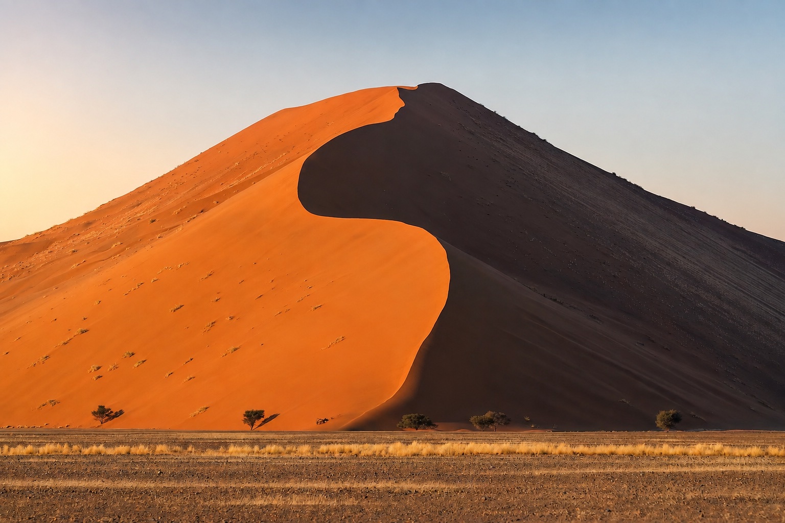 AI-enhanced view: Sunrise lights the orange crest of Dune 45 in Namibia, with a deep shadow on its right face.